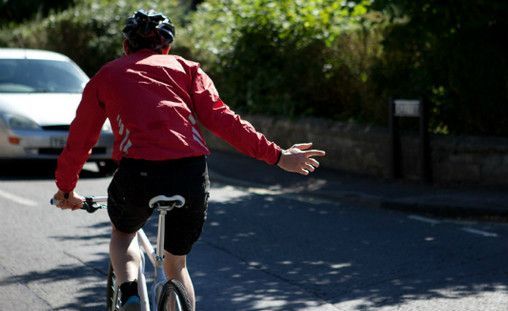 A cyclist holding their arm out to signal