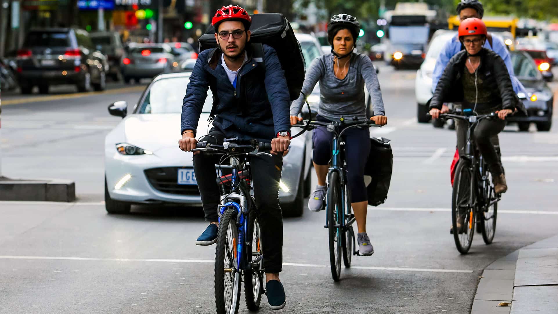 People riding bikes in a traffic lane alongside cars